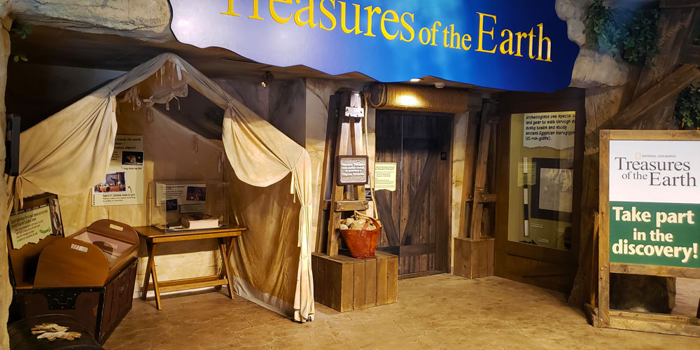 Entrance to the Treasures of the Earth exhibit with objects from the Indiana Jones movie in cases under a canvas tent.